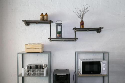 two shelves on a wall with a microwave and a tv at Yindee Travellers Lodge in Nan