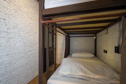 a bed in a room next to a brick wall at Yindee Travellers Lodge in Nan