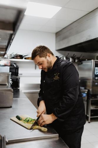 a man in a kitchen preparing food on a cutting board at Hôtel & Restaurant Five Nations in Durbuy