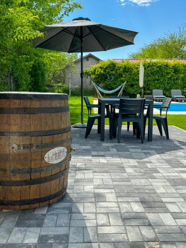 a patio with a table and chairs and an umbrella at LaHuzur Camera Dubla - Therme Balotesti & Aeroport Otopeni in Dumbrăveni