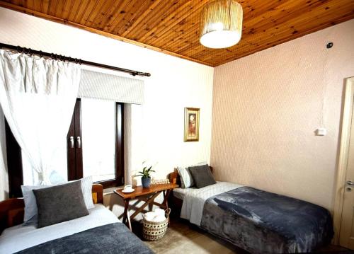 a bedroom with two beds and a table and a window at Charoula Pavliani Fthiotidas in Pavliani