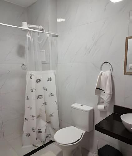 a white bathroom with a toilet and a sink at Refuge Aldeia dos Camarás in Camaragibe