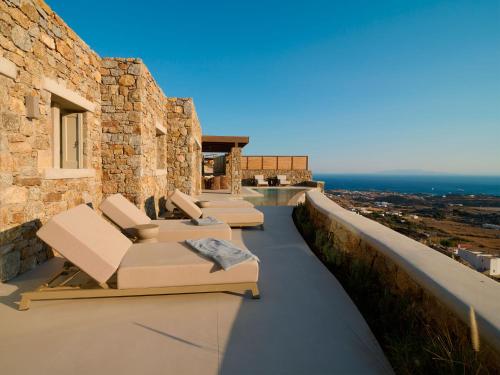 three lounge chairs on the balcony of a house at Mykonos Rocks Villas & Suites in Mýkonos City