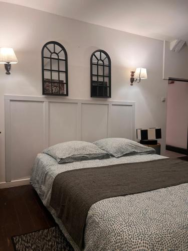 een slaapkamer met een bed en twee ramen aan de muur bij 4 - Les pins roses in Poitiers