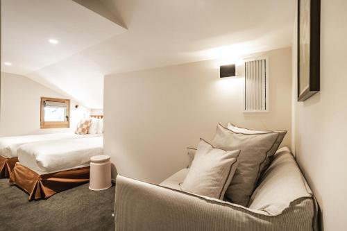a bedroom with a bed and a couch with pillows at Appartements de l'Héliopic in Chamonix-Mont-Blanc