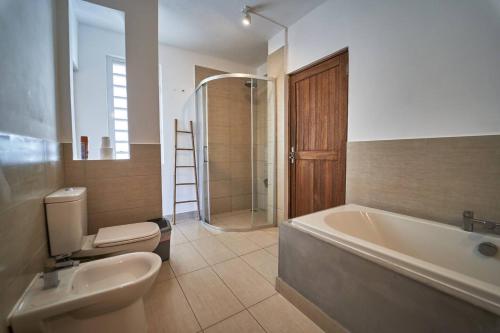 a bathroom with a tub and a toilet and a sink at Loukaz -entire Rental Units W Panoramic Rooftop in La Gaulette