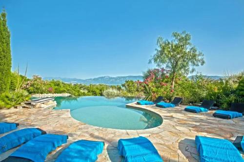 une piscine avec des chaises longues bleues et une piscine dans l'établissement Charmante Maison de Vacances à Olmeto avec Piscine, à Olmeto