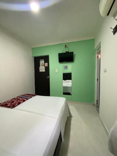 a bedroom with a white bed and a green wall at NaPoles valledupar Hotel in Valledupar