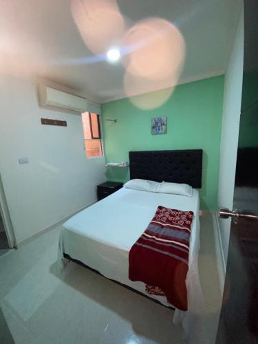a bedroom with a white bed and green walls at NaPoles valledupar Hotel in Valledupar