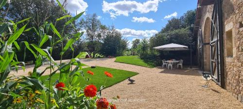 un jardin avec une table et un parasol dans l'établissement Gîte Le Puy Martineau piscine privée intérieure chauffée à 10 min du Puy du Fo, à Saint-Mars-la-Réorthe