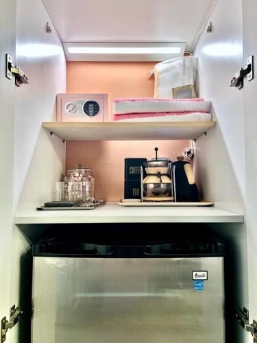 a small kitchen with a shelf above a refrigerator at Double Rainbow Suites 24th in Fort Lauderdale