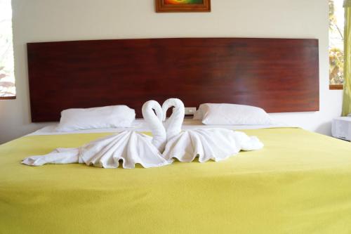 two white swans sitting on top of a bed at Piedras Blancas Lodge in Puerto Ayora
