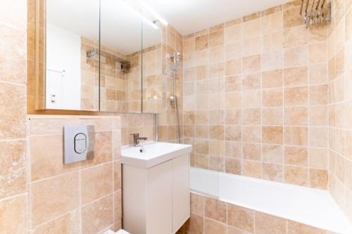 une salle de bain avec un lavabo et une baignoire dans l'établissement Appartement à Megève skis aux pieds - La CABOCHE, à Le Planellet