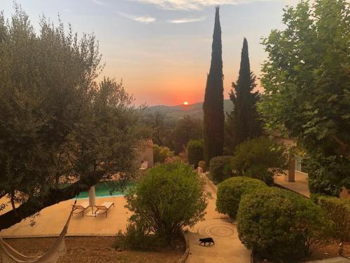 a sunset over a garden with a pool and trees at Propriété : 300 M² + (25 M² d'annexe / Pool House) sur 5 ha boisé à 10' d'Aix en Provence in Beaurecueil