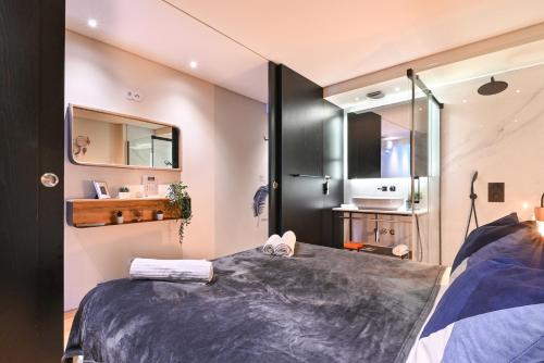 a bedroom with a large bed and a bathroom at Abrigo Muralha By Sé Apartamentos in Braga