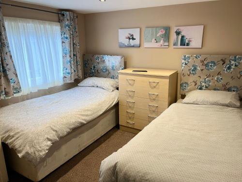 a bedroom with two beds and a dresser at Red Deer Village Holiday Park - 2 Bedroom, Self-Catering Chalet in Steps