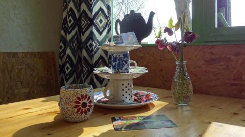 a table with two cups and a vase with flowers at De Horizon, slapen in hutten in Kloosterburen