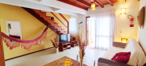 a living room with a couch and a tv at Casa Dos Ventos Hospedagem Praia do Rosa in Praia do Rosa