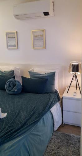 a bedroom with a bed with blue pillows and a lamp at Light Brown Central Apartment in Aveiro