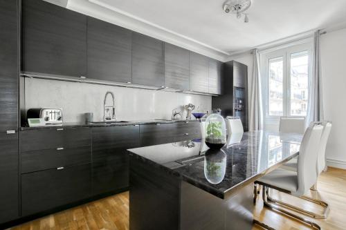 une cuisine avec des armoires noires et un comptoir en verre dans l'établissement Appartement au coeur du 17eme, à Paris