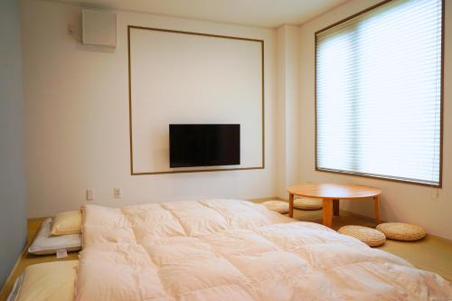 a bedroom with a bed and a tv on the wall at wanderlust STAY in Kofu