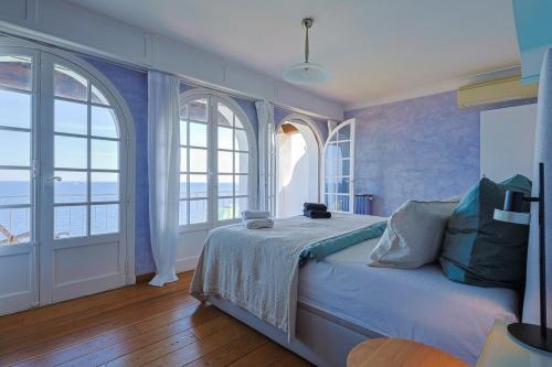 a bedroom with a bed with two large windows at Villa avec vue panoramique et piscine à Saint-Raphael in Saint-Raphaël
