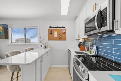 a kitchen with white cabinets and blue tiles on the wall at Sea Cabin 118 - Oceanfront in Myrtle Beach