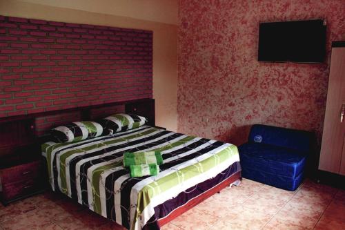 a bedroom with a bed and a tv and a chair at Quinta Los Pinos Cotoca in Cotoca