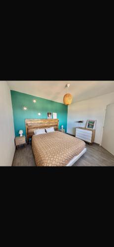 une chambre avec un grand lit et un mur bleu dans l'établissement Grand appartement lumineux 6 personnes, à Martigues