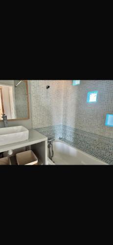 une salle de bain avec une baignoire et un lavabo dans l'établissement Grand appartement lumineux 6 personnes, à Martigues