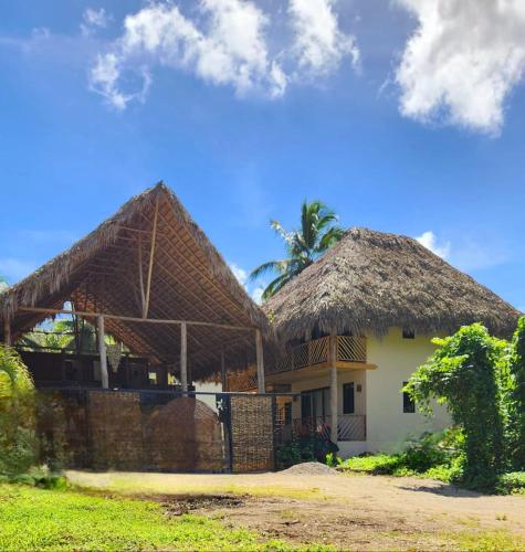 two houses with thatched roofs with a palm tree in the background at Boho villas and spa in El Valle