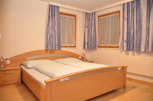 a bedroom with a wooden bed with blue curtains at Haus Gentiana in Samnaun