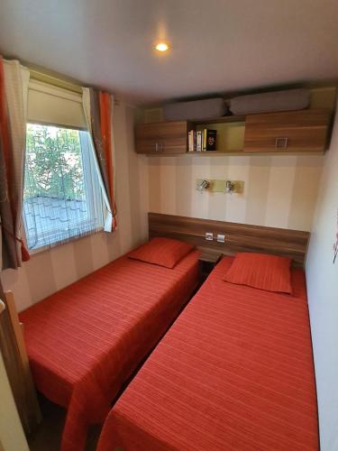 - 2 lits dans une petite chambre avec des draps rouges dans l'établissement Camping les Salins de la Gardiole, à Vic-la-Gardiole