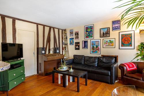 - un salon avec un canapé en cuir noir et une télévision dans l'établissement GuestReady - Classic Parisian stay near Bastille, à Paris