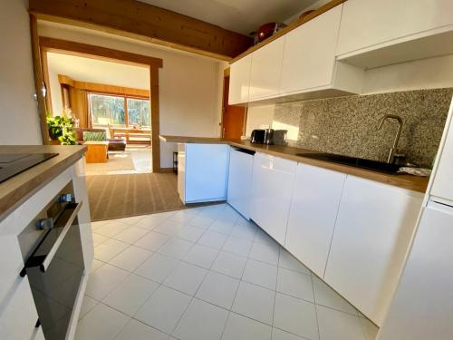Una cocina con gabinetes blancos y piso de baldosas. en Apartment Chamonix Brise du Mont, en Chamonix-Mont-Blanc