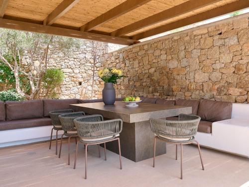 a patio with a table and chairs and a stone wall at Mykonos Rocks Villas & Suites in Mýkonos City