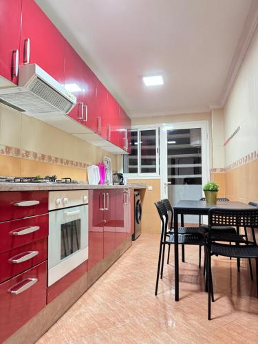 a kitchen with red cabinets and a table and chairs at SUITOUISS - Agdal 2 - Appartements à 2 minutes de la gare de train TGV Rabat in Rabat