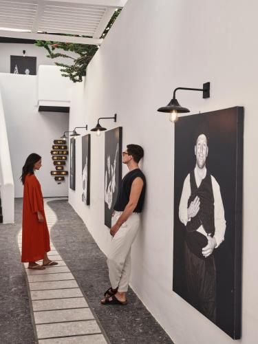 a group of people looking at art on a wall at Myconian Avaton, a Member of Design Hotels in Elia Beach