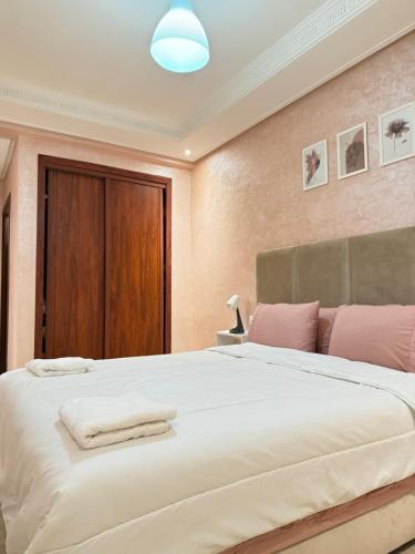 a bedroom with a large white bed with pink pillows at SUITOUISS - Agdal 2 - Appartements à 2 minutes de la gare de train TGV Rabat in Rabat