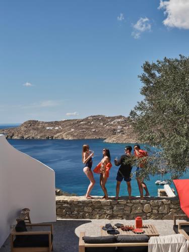 a group of people standing on a wall near the water at Myconian Avaton, a Member of Design Hotels in Elia Beach