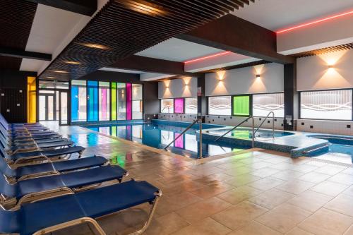 a swimming pool with blue chairs and stained glass windows at Altus Hotel & Spa in Praid