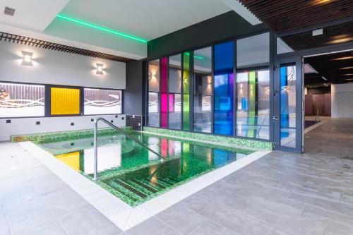 a pool in a building with colorful windows at Altus Hotel & Spa in Praid