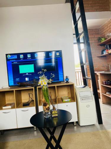 a living room with a tv and a table with flowers at Mordern Lil' Love Nest Loft in Midrand in Midrand