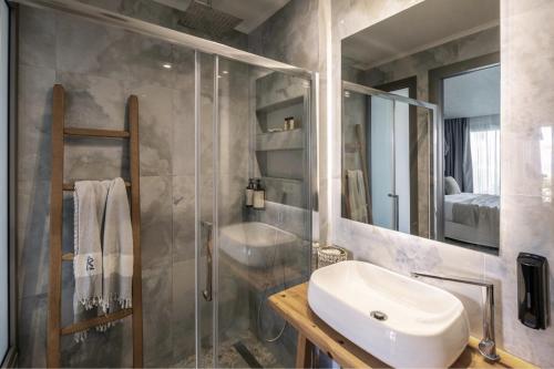 łazienka z umywalką i przeszkloną kabiną prysznicową w obiekcie Blue Carpet Luxury Suites w mieście Pefkochori