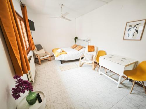 a room with a bed and chairs and a desk at El Penell Estudi Mestral in Vilamaniscle