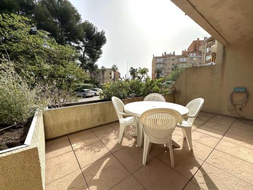 - une table et des chaises blanches sur la terrasse avec vue dans l'établissement HYEDES Appartement climatisé pour 4 personnes sur le port de Hyères, à Hyères