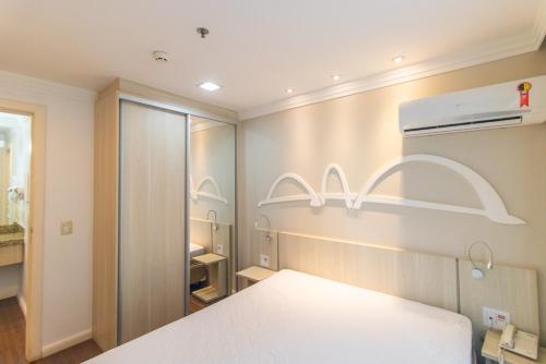 une chambre avec un lit blanc et un placard dans l'établissement Hotel Mercure, à Brasilia