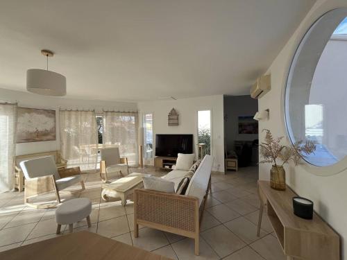 un salon avec des meubles blancs et une grande fenêtre dans l'établissement PORT CAMARGUE - JOLIE VILLA POUR 6 PERSONNES CLIMATISEE AVEC JARDIN ET PARKING, au Grau-du-Roi