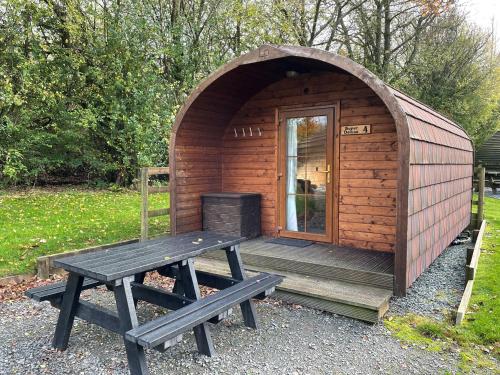a wooden cabin with a picnic table and a bench at Woodclose Park in Kirkby Lonsdale