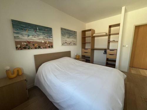 Cet appartement comprend une chambre avec un lit blanc et une cuisine. dans l'établissement PORT CAMARGUE - JOLIE VILLA POUR 6 PERSONNES CLIMATISEE AVEC JARDIN ET PARKING, au Grau-du-Roi
